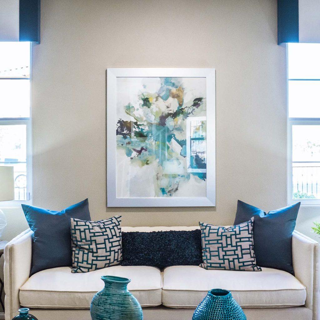 a custom designed living room with a blue and white theme including throw pillows, blinds, and table decorations