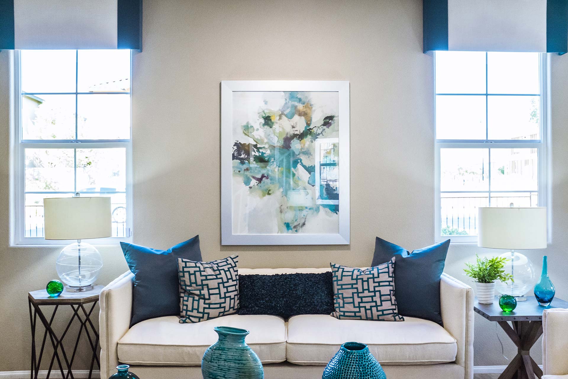 a custom designed living room with a blue and white theme including throw pillows, blinds, and table decorations